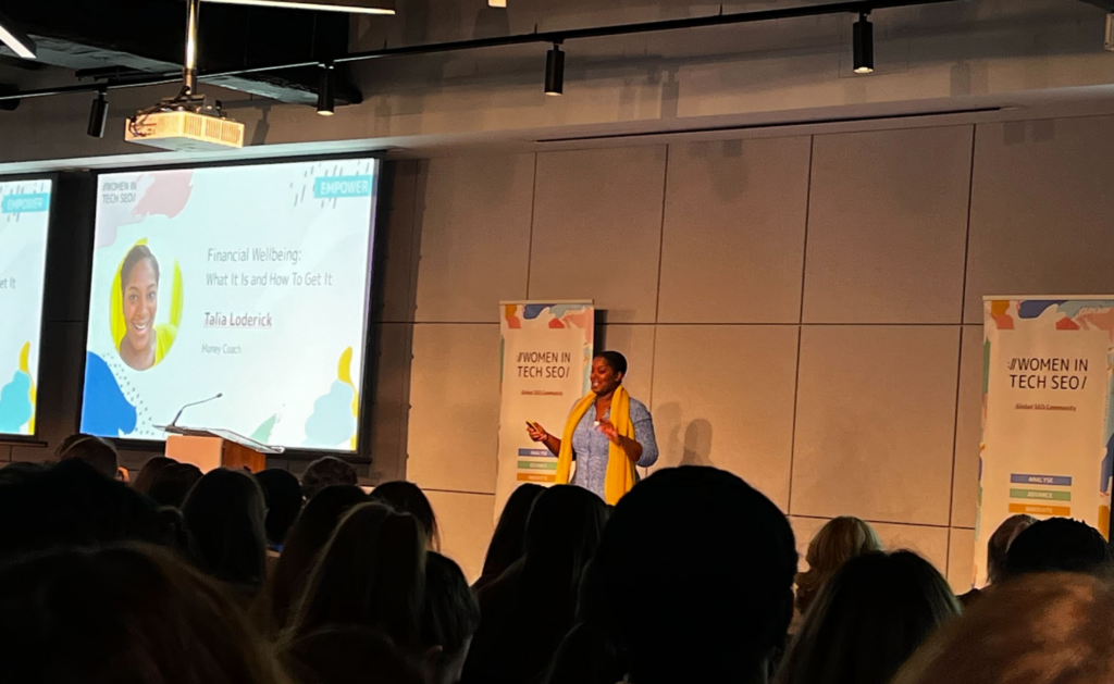 On stage at the Women in Tech SEO (WTS) conference in London: Talia Loderick discusses financial wellbeing for women professionals.